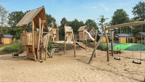 A wooden playground with slides and swings, surrounded by trees and a green field. - Pet friendly home in Mariënberg (Mariënberg)