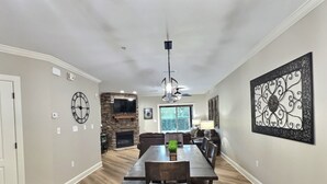 A spacious living room with a stone fireplace, a large flat-screen TV, and a dining area with a granite table.
