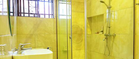 Un baño moderno con ducha de vidrio, lavamanos y espejo.