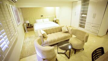 Ein Schlafzimmer mit Bett, Sofa, Sessel, einem kleinen Tisch und einem Kleiderschrank.