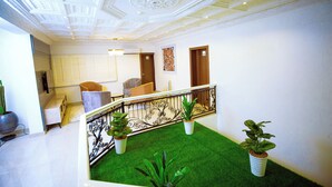 Un vaste espace de vie doté d’un haut plafond, d’un balcon avec une balustrade et de plantes en pot.
