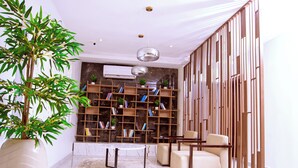 Un salon moderne avec une grande plante en pot, un canapé, une table basse et une bibliothèque.
