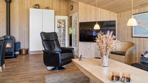 A cozy living room with a black leather chair, a wooden coffee table, and a fireplace.