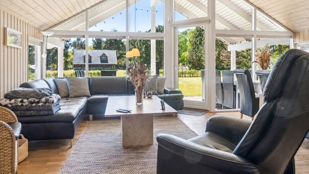 A spacious living area with a large window, a sofa set, a coffee table, and a chair.