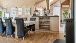 A modern kitchen with wooden paneling, a dining area with black chairs, and a wine rack.