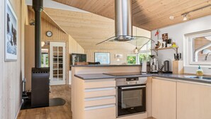A modern kitchen with wooden cabinetry, a built-in oven, and a stainless steel range hood.