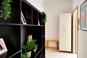 A room with a black shelving unit, a white cabinet, a wooden bench, and a door with a phone.