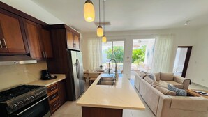 A modern kitchen with a central island, a dining area, and a living room with a sofa.