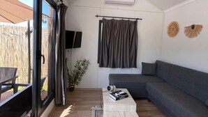 A modern living room with a large window, a grey sectional sofa, a small coffee table, and a flat-screen TV.