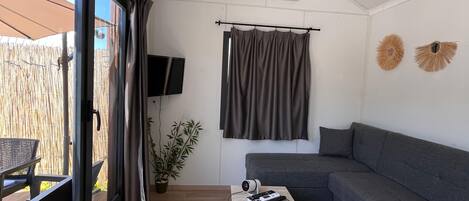 Una sala de estar moderna con un ventanal grande, un sofá seccional gris, una mesita de centro pequeña y un televisor de pantalla plana.
