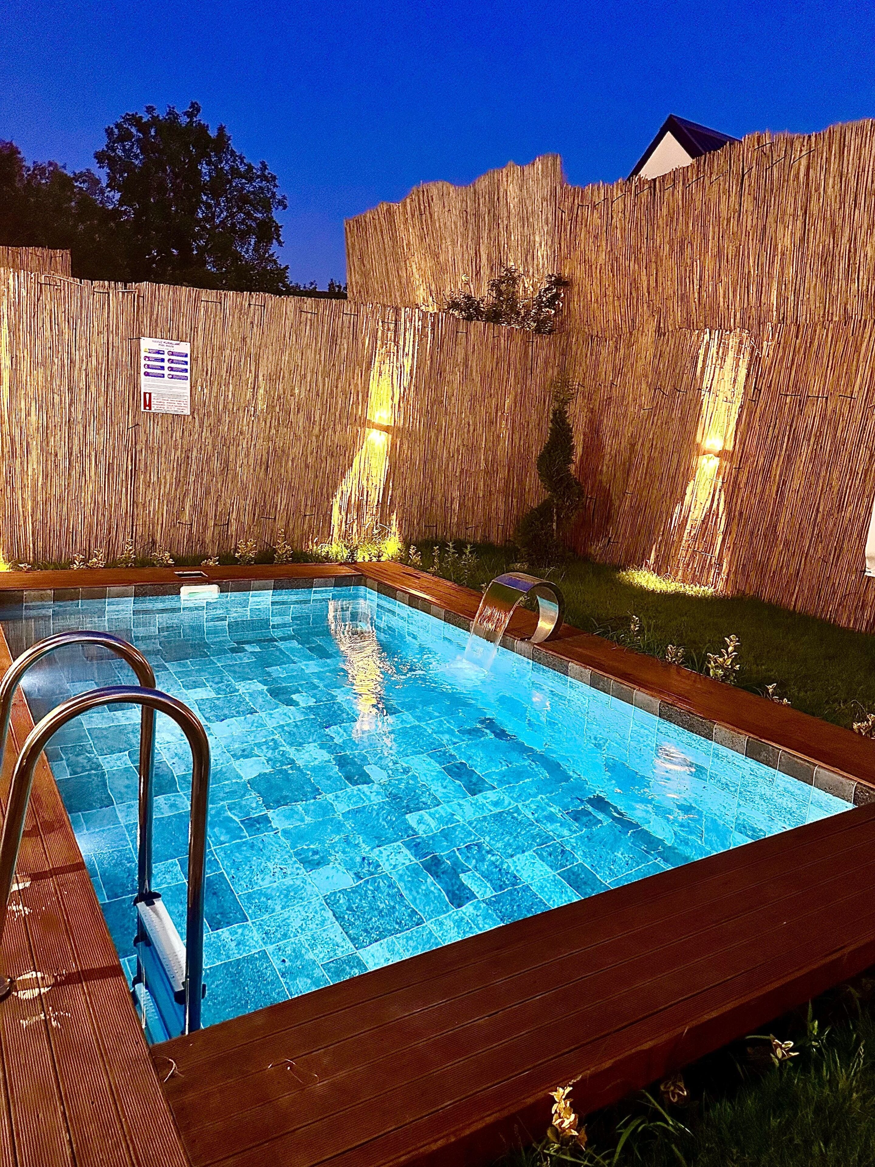 Ein Schwimmbecken mit Holzterrasse und Bambuszaun.