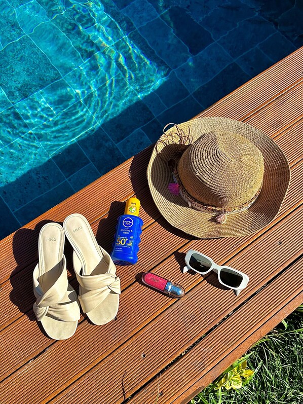 A wooden deck by a pool with a straw hat, sunglasses, sunscreen, and sandals. - Sesa Sapanca (Sapanca)