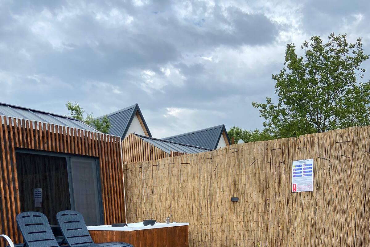 A swimming pool with a wooden deck, lounge chairs, and a wooden fence.