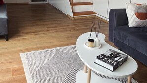 A modern living room with a staircase, a sofa, a coffee table, and a rug.