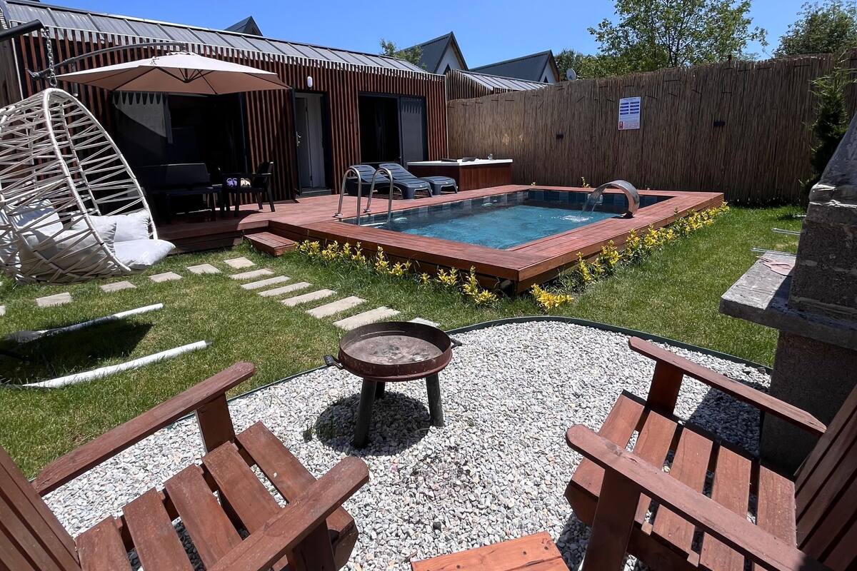 A backyard with a pool, wooden deck, and outdoor seating.