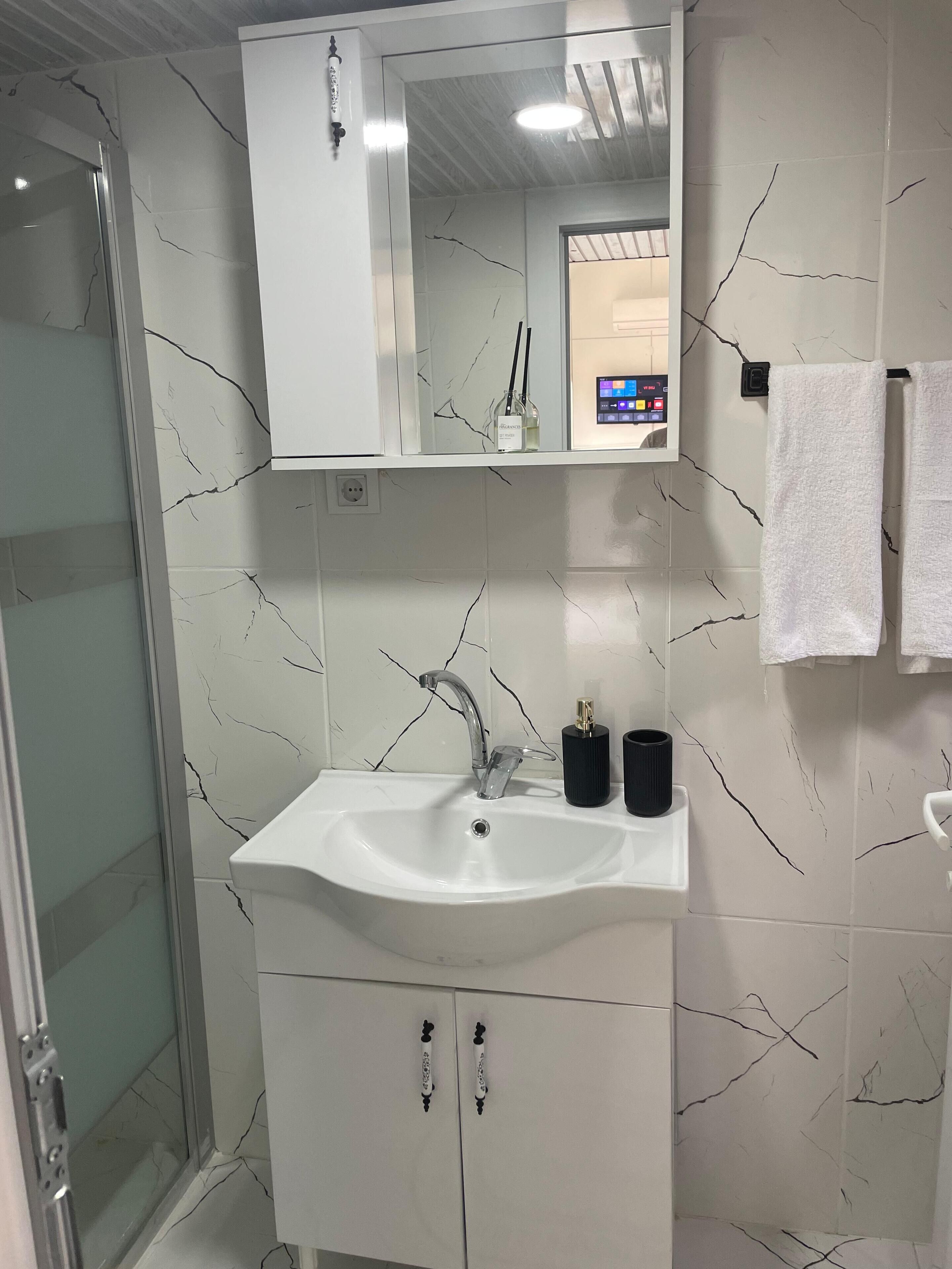 Un bagno con un lavandino bianco, uno specchio e una doccia.