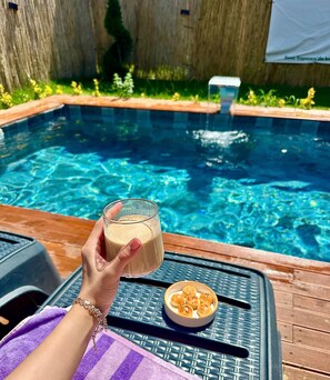 A person holding a glass of beverage by a poolside with a bowl of snacks. - Sesa Sapanca (Sapanca)