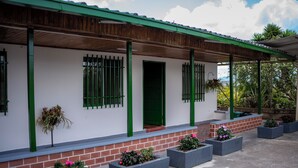 Un edifici amb una porta verda, un porxo cobert i planters rectangulars amb flors.