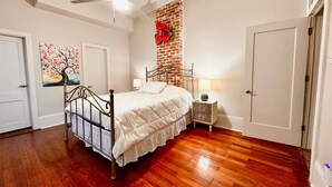 A bedroom with a bed, a nightstand, a wall clock, and a door. - Beautiful 3-bedroom house close to the Super Bowl and French Quarter! Book now (New Orleans)