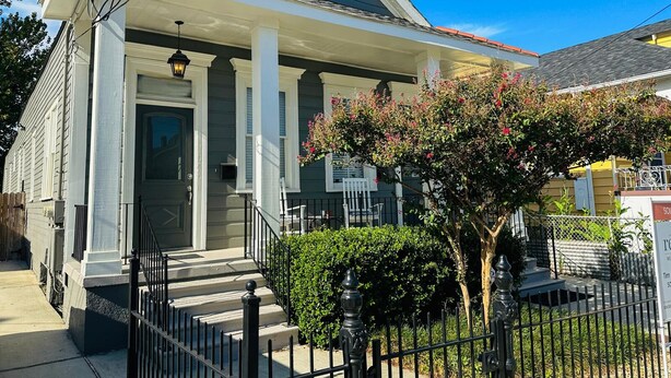 A two-story house with a front porch, a small garden, and a black metal fence. - Beautiful 3-bedroom house close to the Super Bowl and French Quarter! Book now (New Orleans)