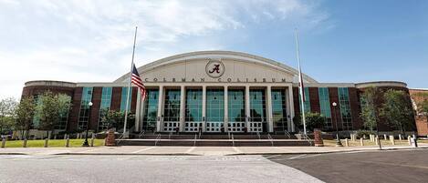 A large, modern building with a prominent 'A' logo, wide steps leading to the entrance, and two flagpoles with flags.