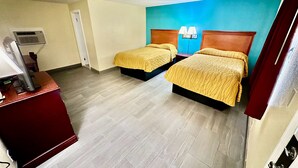 A hotel room with two beds, a desk with a computer, and a wall-mounted air conditioner. - Bel-Aire Motel Tuscaloosa (Tuscaloosa)