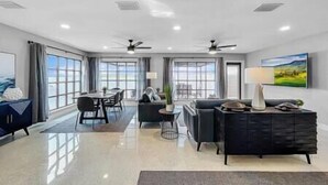 A spacious living area with a dining table, sofas, and a large window offering a view.