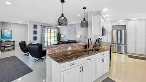 A modern kitchen with white cabinets, a marble countertop, and stainless steel appliances.