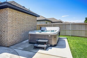 Een hottub in een achtertuin, met een bakstenen muur en een houten omheining.