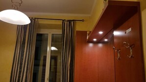 A room with a wooden wardrobe, a hanging light fixture, and a window with curtains. - HOLIDAY ROMA (Rome)