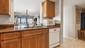 A kitchen with wooden cabinets, a white microwave, and a dishwasher. - Oceanfront condo w 2 pools, private balcony & beach access. Short walk to The Ritz-Carlton (Amelia Island)