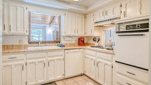 A kitchen with white cabinetry, a built-in oven, and a window. - Fireplace | Pool Table | WiFi | Hot Tub | Deer Haven (Angel Fire)