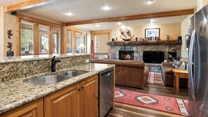 Una cocina con encimeras de granito, gabinetes de madera, lavavajillas y chimenea de piedra.