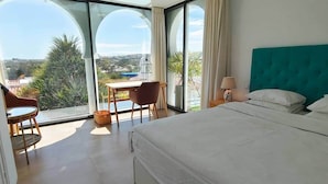 Une chambre d’hôtel moderne dotée d’un grand lit, d’un bureau avec une chaise et offrant une vue sur la ville grâce à de grandes fenêtres.