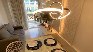 A dining area with a table set for four, including plates, cutlery, and glasses. - Flat 110 Muro Alto CC by LaPlaya (Ipojuca)