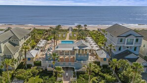 A resort with a pool, palm trees, and a beach view.