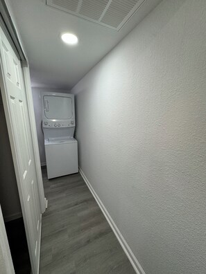 A laundry room with a washing machine and dryer, a white door, and a textured wall.