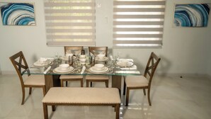 A dining area with a glass table set for six, surrounded by wooden chairs with cushioned seats. - North Ritz Villa - 1 Bedroom Apartment (Ocho Rios, Draxhall, St Ann, Jamaica)