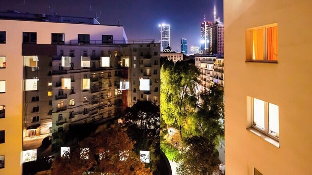 Ein Nachtblick auf ein Wohngebiet mit mehrstöckigen Gebäuden, von denen einige beleuchtete Fenster haben, und einige Hochhäuser im Hintergrund.