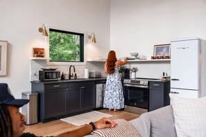 A modern kitchen with dark cabinets, a microwave, a stove, and a refrigerator.