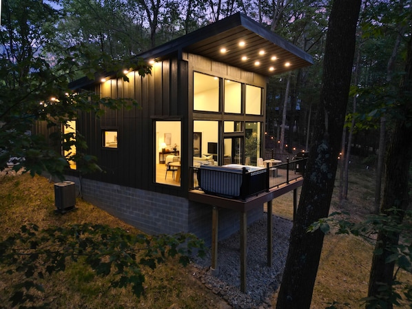 A modern cabin with a deck, large windows, and a cozy interior.