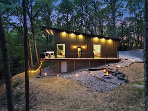A cabin with a deck, a fire pit, and a stone pathway.