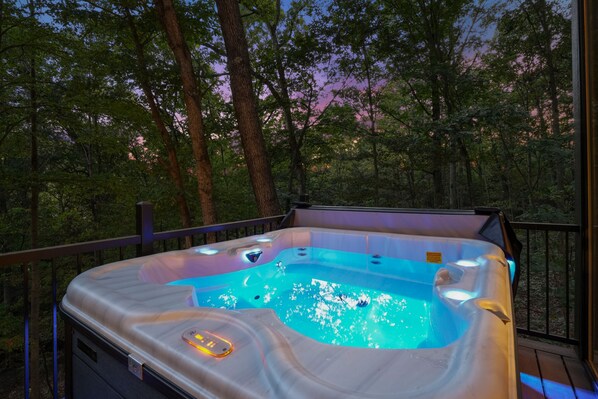 A hot tub on a deck with a view of a forested area.