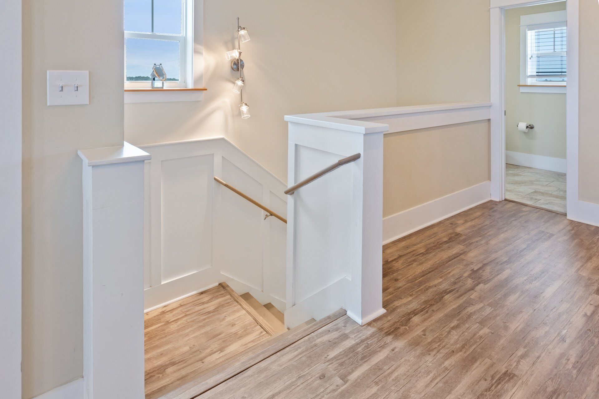 A staircase with a wooden handrail, white walls, and a wooden floor.