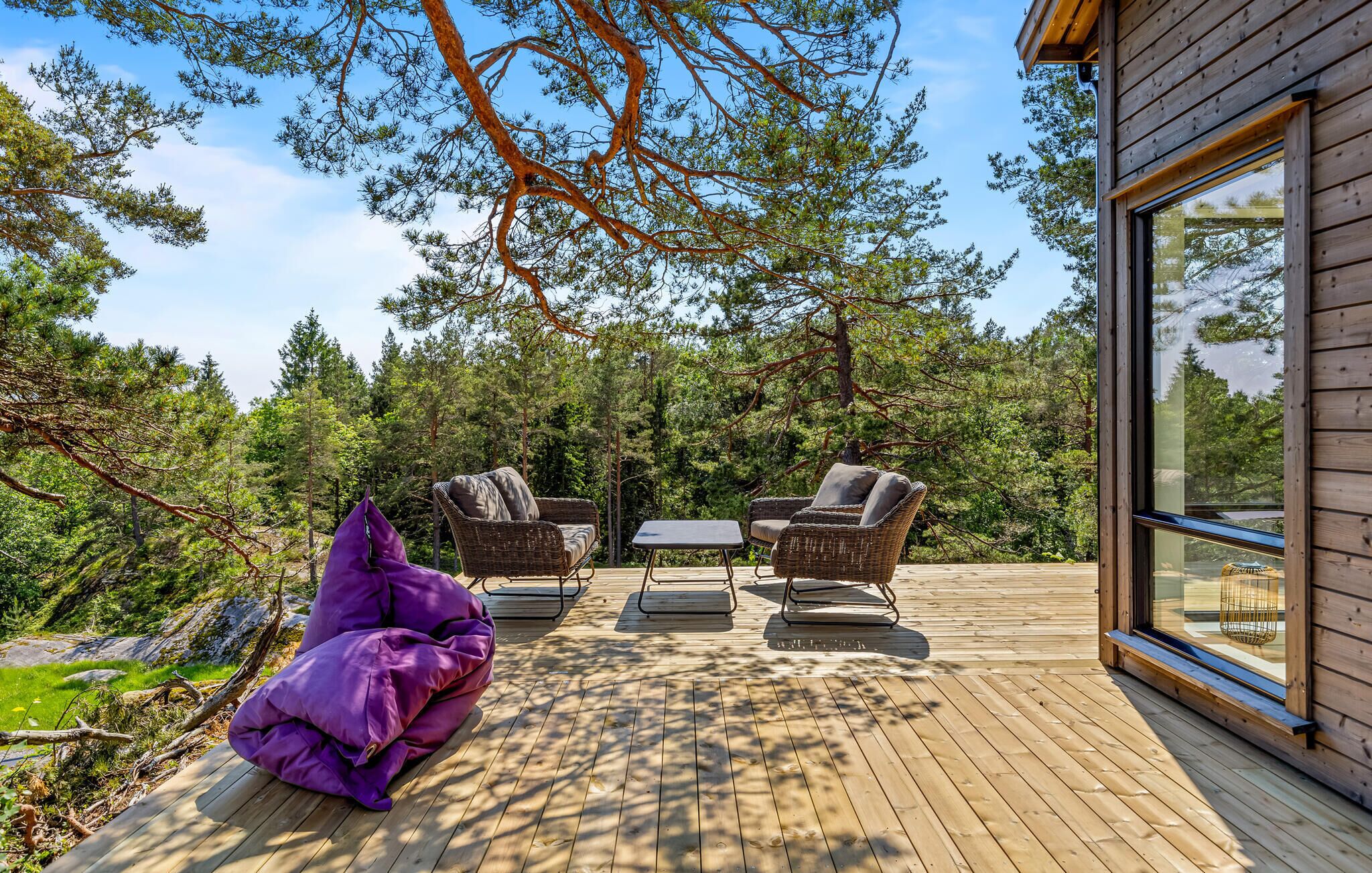 A wooden deck with wicker furniture and a purple bean bag chair.