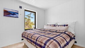 A bedroom with a bed, a window with a view of trees, and a painting on the wall. - 4 bedroom lovely home in Risør (Risør)