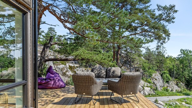 A wooden deck with wicker furniture and a purple bean bag chair. - 4 bedroom lovely home in Risør (Risør)
