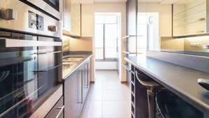 A modern kitchen with stainless steel appliances, a central island, and a view to the dining area.
