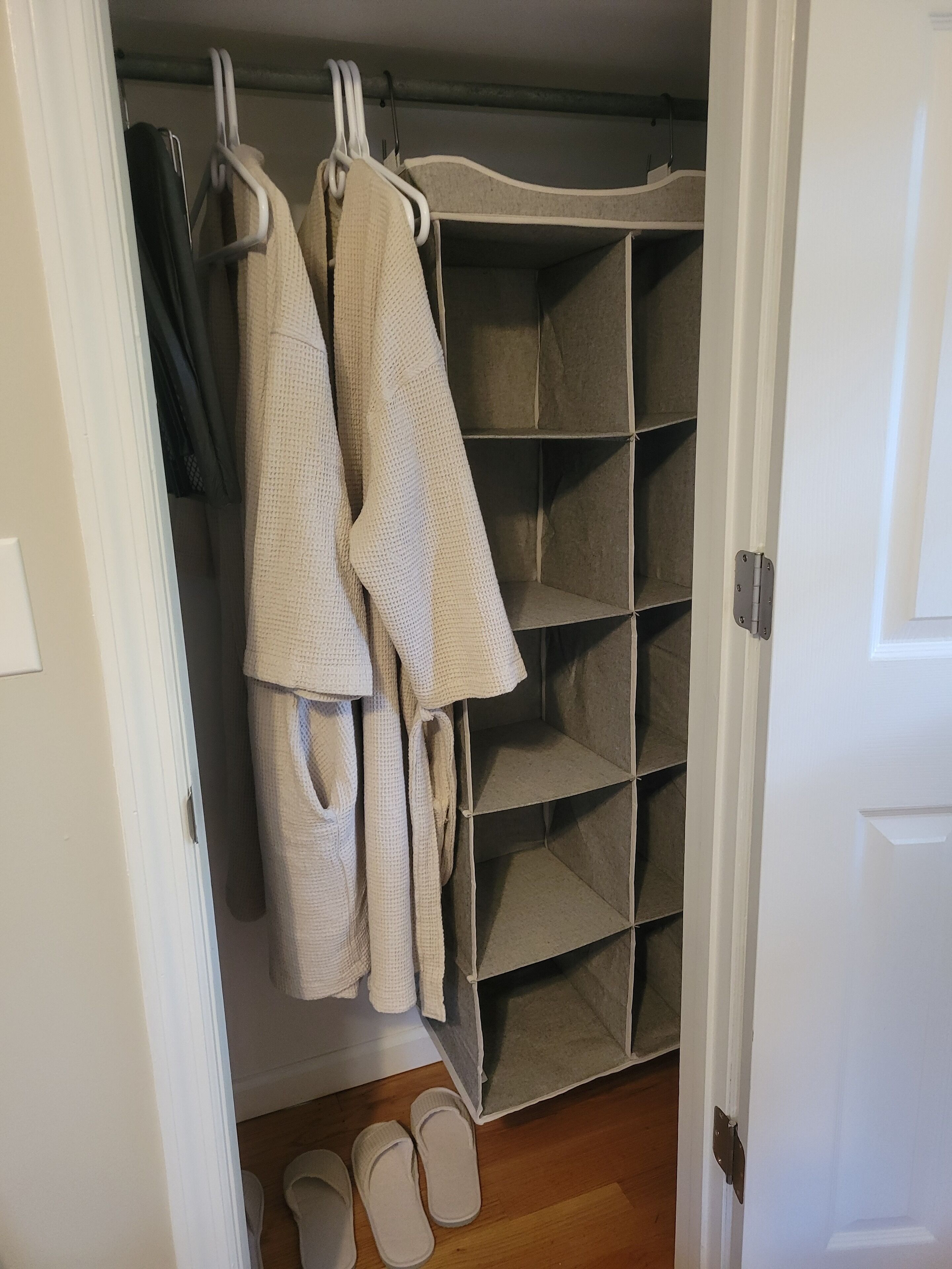 A walk-in closet with hanging robes and shelves.