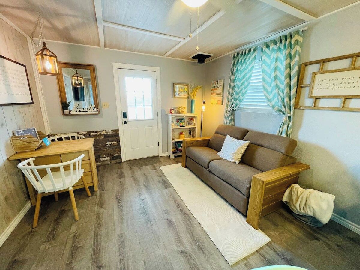 Un salon chaleureux avec un plancher en bois, un canapé marron, un fauteuil blanc et une petite table.